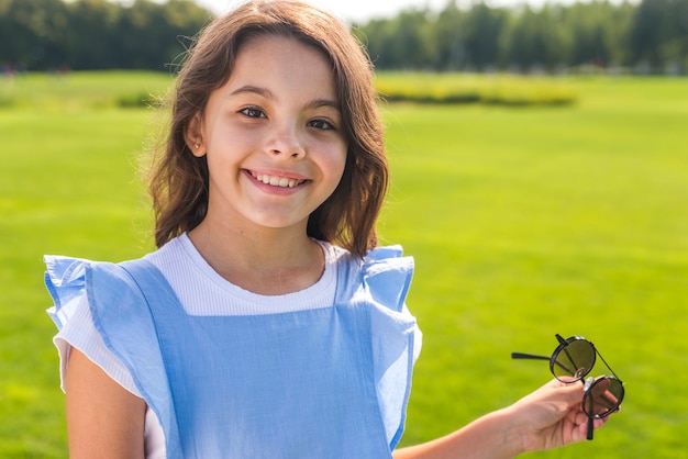 Kleines Mädchen der Vorderansicht, das kühle Sonnenbrille hält