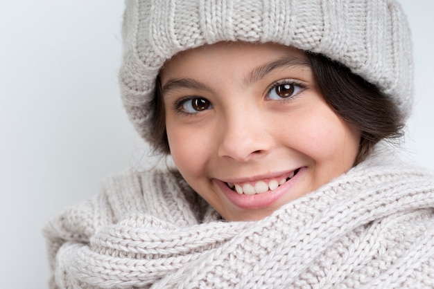 Kleines Mädchen des Brunette mit einem starken Halstuch und einem Hut