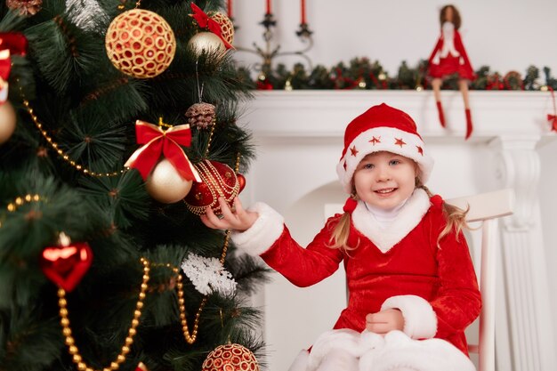 Kleines Mädchen, die eine Weihnachtskugel hält