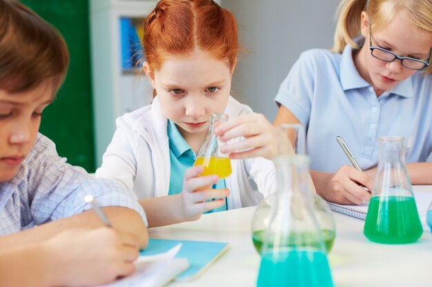 Kleines Mädchen, die Flasche in der Chemie-Klasse Analyse