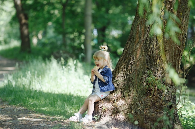 Kleines Mädchen ein Eis lehnt an einem Baum zu essen