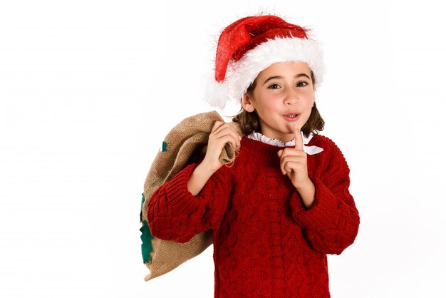 Kleines Mädchen gekleidet als Weihnachtsmann lacht und für Stille mit einem braunen Sack zu fragen