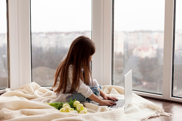 Kostenloses Foto kleines mädchen im bett mit laptop