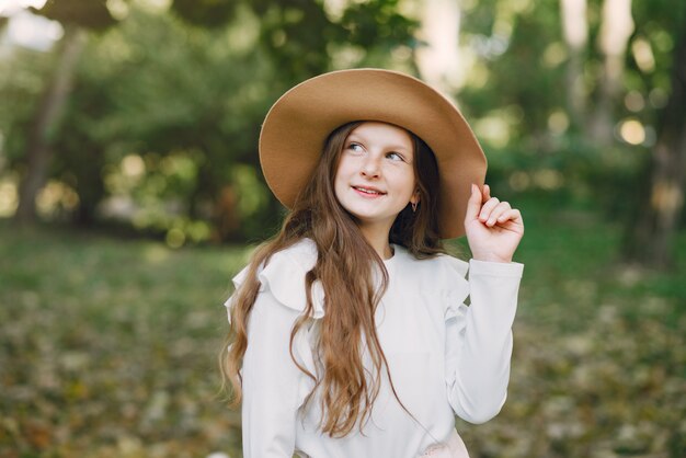 Kleines Mädchen in einem Park, der in einem Park in einem braunen Hut steht