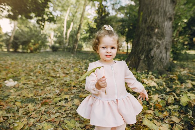 Kleines Mädchen in einem Park in einem rosa Kleid spielen