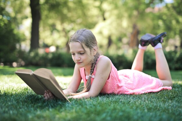 kleines Mädchen in einem Park liest ein Buch