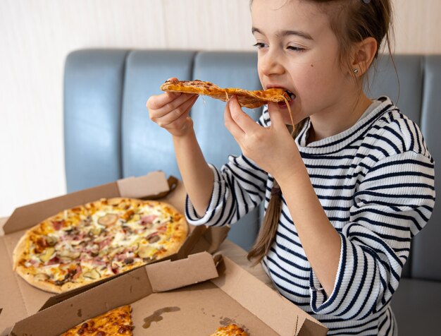 Kleines Mädchen isst appetitliche Käsepizza zum Mittagessen.