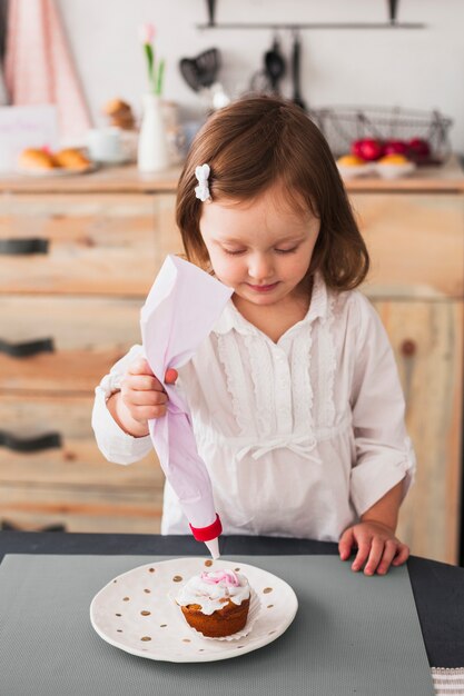 Kleines Mädchen macht Cupcake