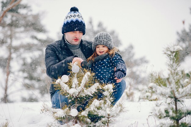 Kleines Mädchen mit dem Vater, der in einem Winterpark spielt