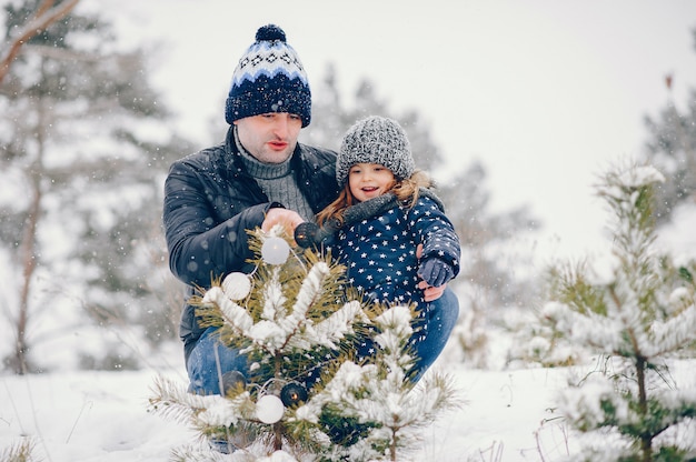 Kleines Mädchen mit dem Vater, der in einem Winterpark spielt