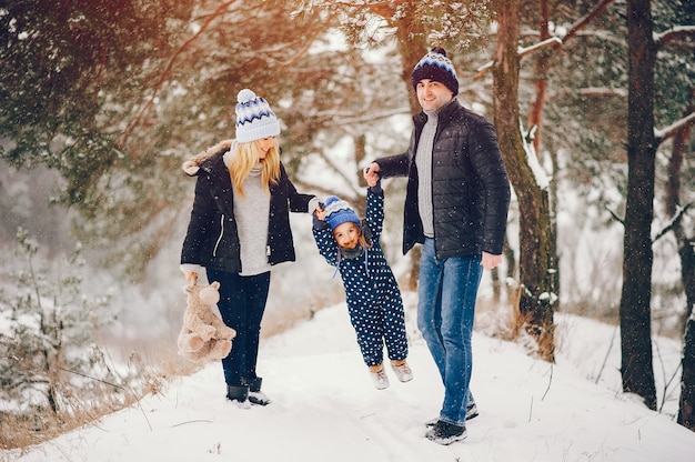 Kleines Mädchen mit den Eltern, die in einem Winterpark spielen