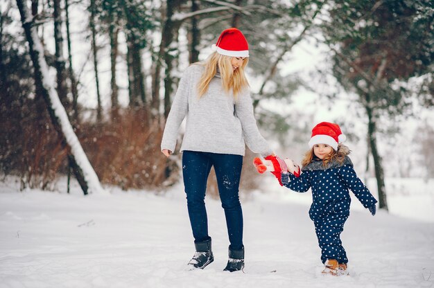 Kleines Mädchen mit der Mutter, die in einem Winterpark spielt