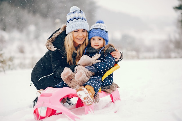 Kleines Mädchen mit der Mutter, die in einem Winterpark spielt