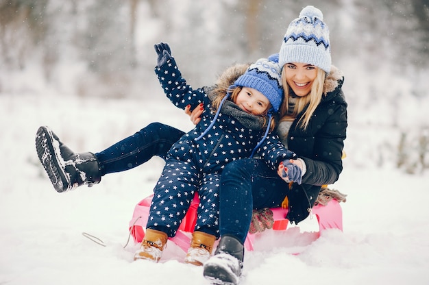 Kostenloses Foto kleines mädchen mit der mutter, die in einem winterpark spielt