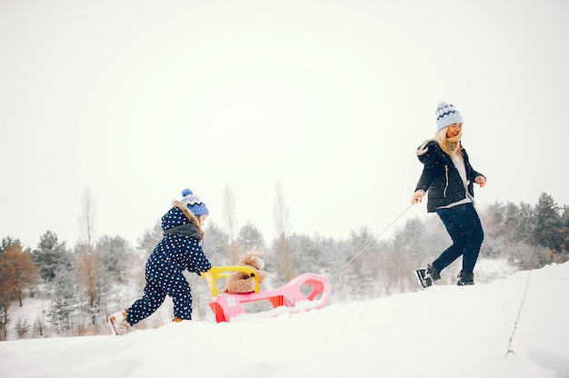 Kleines Mädchen mit der Mutter, die in einem Winterpark spielt