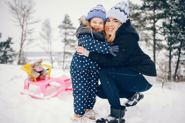 Kleines Mädchen mit der Mutter, die in einem Winterpark spielt