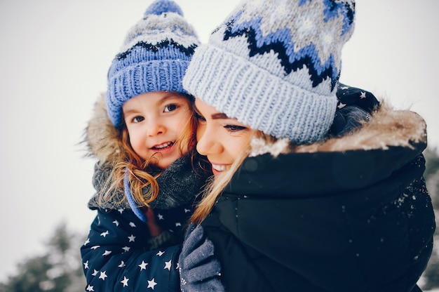 Kleines Mädchen mit der Mutter, die in einem Winterpark spielt