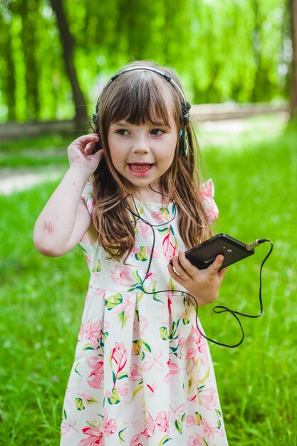 Kleines Mädchen mit einem Handy Musik hören