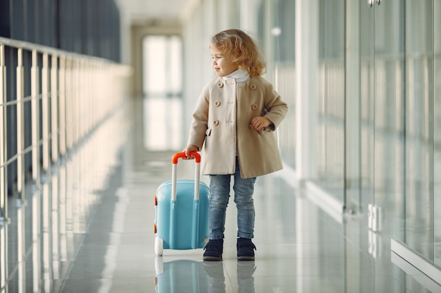 Kleines Mädchen mit einem Koffer am Flughafen