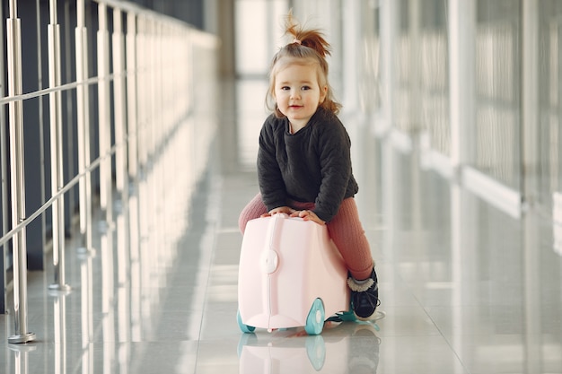 Kleines Mädchen mit einem Koffer am Flughafen