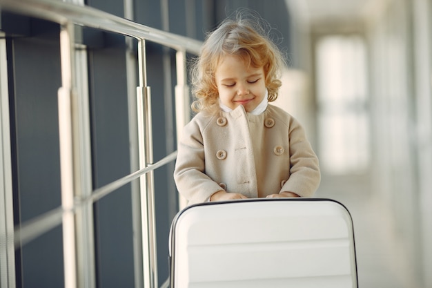 Kleines Mädchen mit einem Koffer am Flughafen