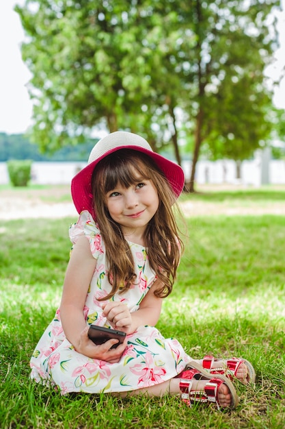 Kostenloses Foto kleines mädchen mit einem smartphone lächelnd