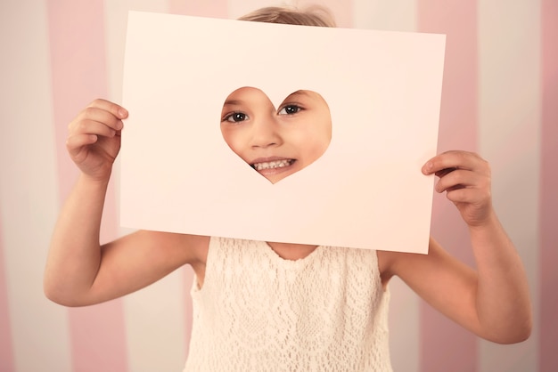 Kostenloses Foto kleines mädchen mit karte für valentinstag