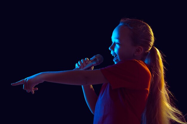 Kleines Mädchen mit Mikrofon im Neonlicht