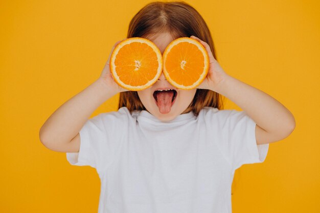 Kleines Mädchen mit Orangen isoliert im Studio