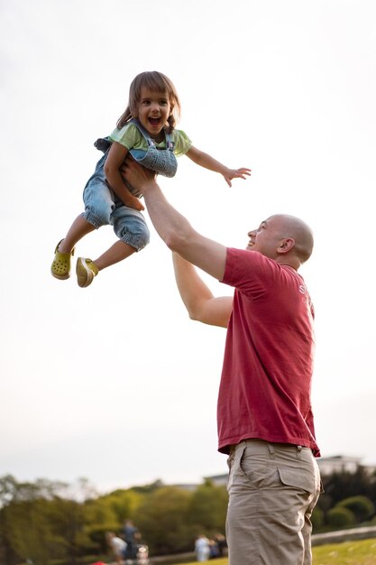 Kleines Mädchen mit Papa. Vater wirft Baby in die Luft. fröhliches Lachen, emotionales Kind, Glück.