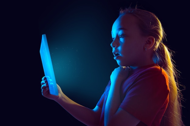 Kleines Mädchen mit Tablette im Neonlicht