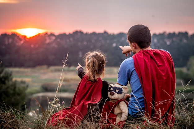 kleines Mädchen mit Vater gekleidet in Superhelden, glückliche liebende Familie
