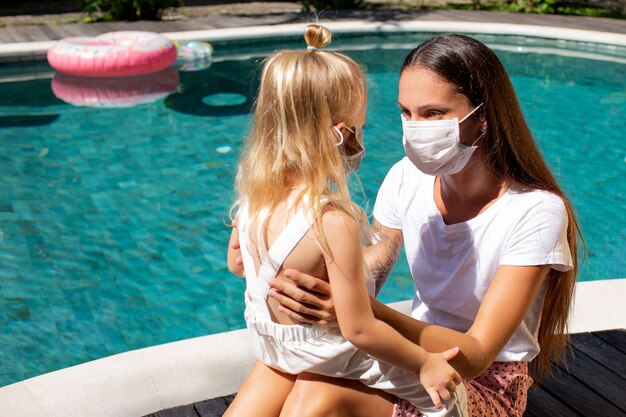 Kleines Mädchen setzt eine Maske für Mama auf. Hochwertiges Foto