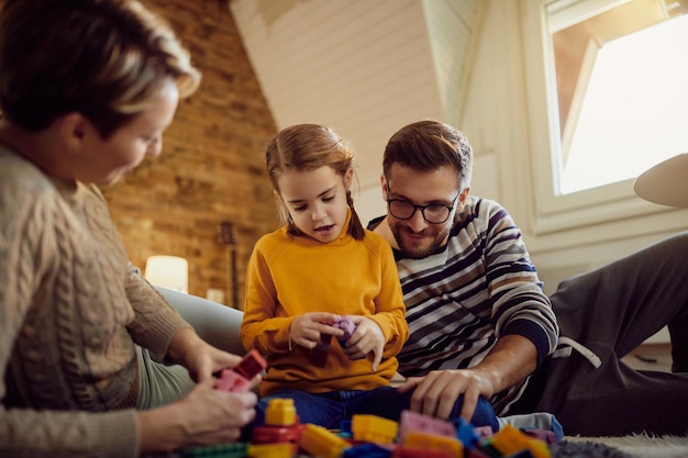 Kostenloses Foto kleines mädchen und ihre eltern spielen mit spielzeugklötzen im wohnzimmer