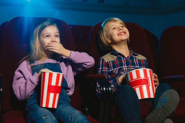 Kleines Mädchen und Junge, die einen Film in einem Kino ansehen
