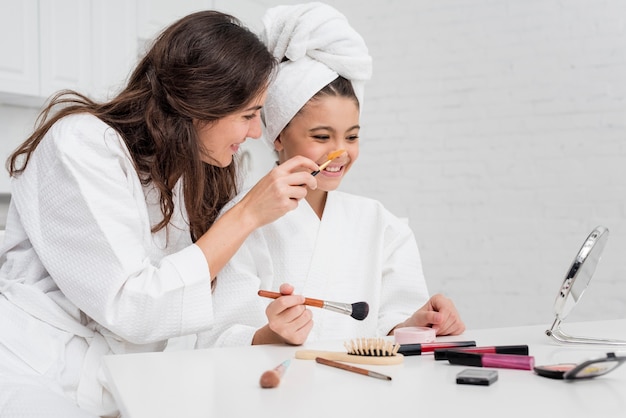 Kleines Mädchen und Mutter, die zusammen ihr Make-up tut