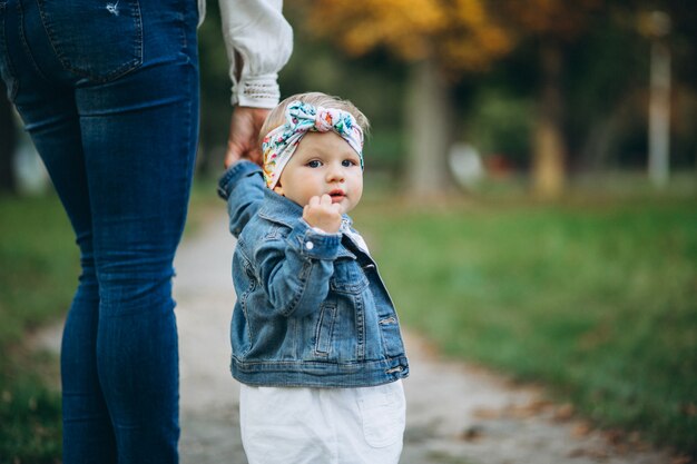 Kleines Mädchen, welches die Hand der Mutter im Park hält