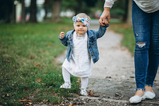 Kleines Mädchen, welches die Hand der Mutter im Park hält