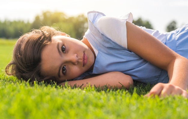 Kleines Mädchen, welches die Kamera beim Bleiben auf Gras betrachtet