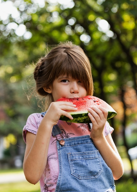 Kleines Mädchen, welches die Wassermelone im Freien genießt