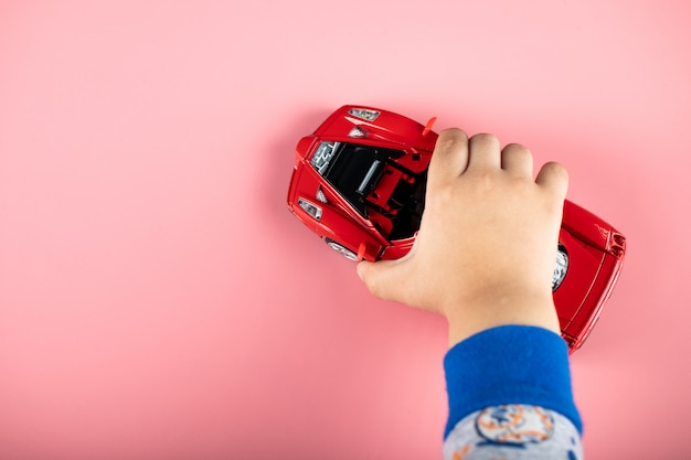 Kleines rotes Autospielzeug für ein Kind, ein Kind, das damit spielt