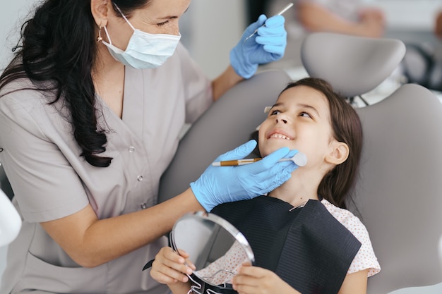 Kleines schönes Mädchen beim Zahnarzt lächelnd