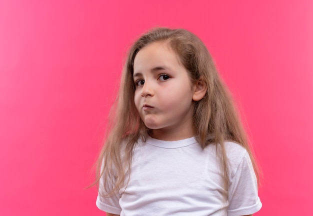 kleines Schulmädchen, das weißes T-Shirt auf isolierter rosa Wand trägt