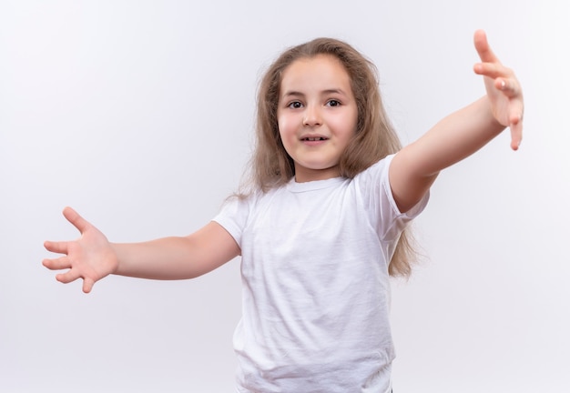 Kostenloses Foto kleines schulmädchen, das weißes t-shirt trägt, das größe auf isolierter weißer wand zeigt