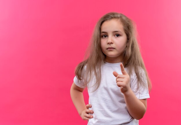 kleines Schulmädchen, das weißes T-Shirt trägt, das Sie Geste auf isolierter rosa Wand zeigt