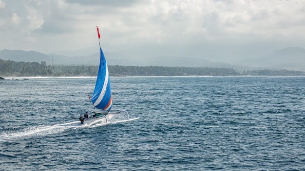 Kleines Segelboot schwimmt auf dem Wasser mit herrlichem Bergblick.