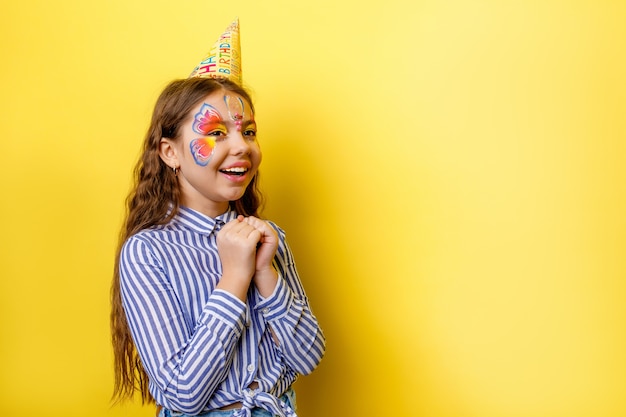 Kleines süßes Geburtstagskind in Partymütze mit Posing isoliert auf einer gelben Wand