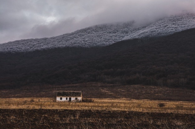 Kleines weißes einzelnes haus in einem feld mit nebel auf dem berg