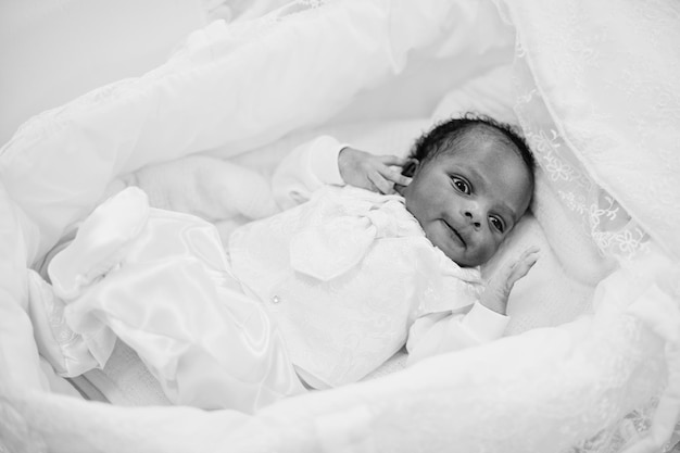 Kleines winziges neugeborenes afroamerikanisches Baby, das auf dem Bett liegt Schwarz-Weiß-Foto
