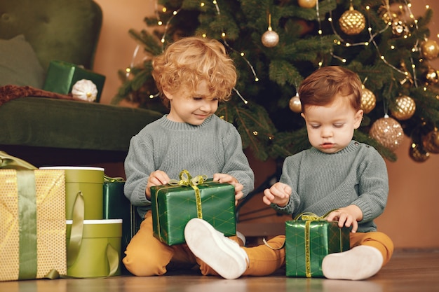 Kleinkinder nähern sich Weihnachtsbaum in einer grauen Strickjacke